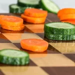 Beitragsbild zum Artikel "Eine ausgewogene Ernährung". Gurken- und Rübenscheiben auf einem Schachbrett.